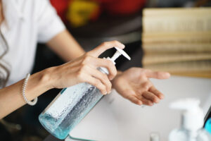 Woman applying hand sanitizer to her hands to avoid pink eye