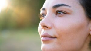 Attractive woman outside looks out into nature without needing to rely on glasses following her EVO ICL procedure.